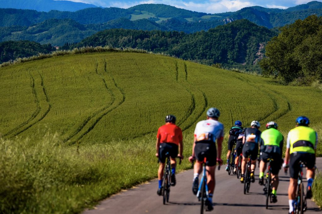 Ciclisti della Nove Colli 2026 affrontano una salita circondati da colline verdi