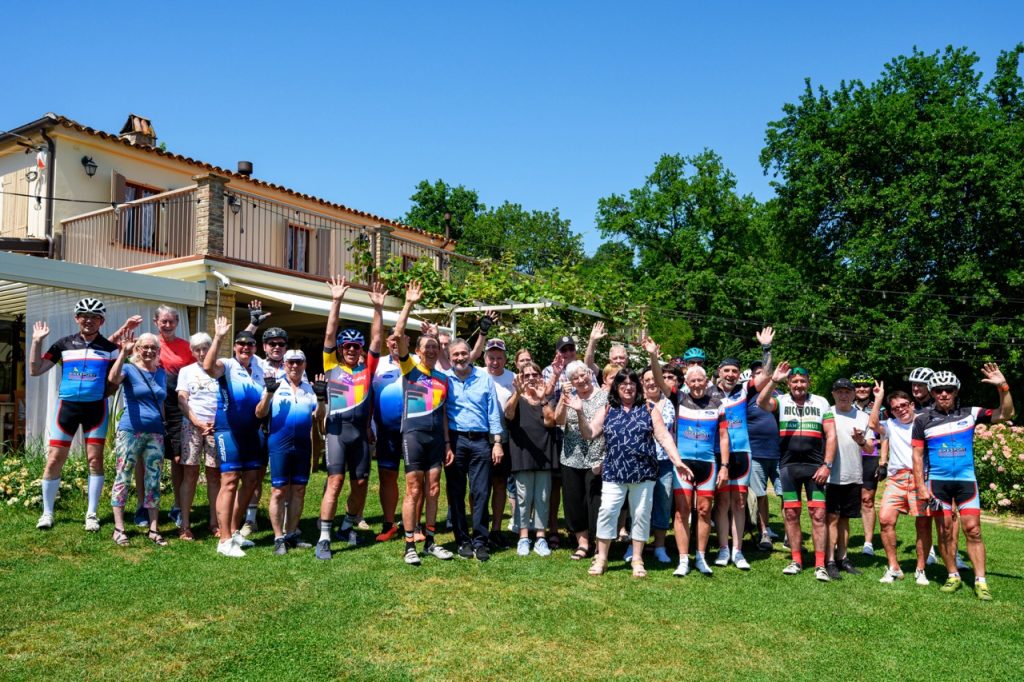 A group of German Riccione Bike Hotels cyclists enjoying a post-ride lunch at a farmhouse organized after a guided tour